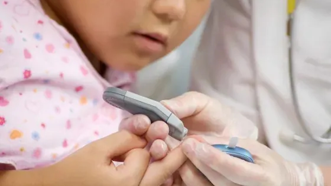 A healthcare worker performing a finger-prick blood glucose test on a child's hand