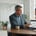 A CRM manager stands to lead a discussion with colleagues seated around a conference table.