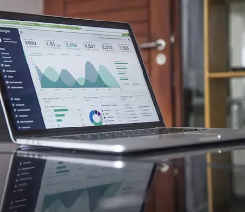 Laptop on a table displaying a dashboard with charts and summary metrics