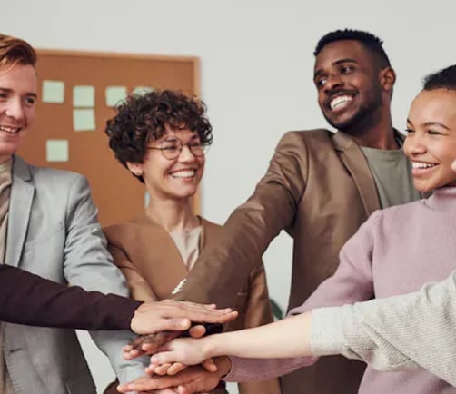 A group of colleagues stacking their hands together in a team huddle