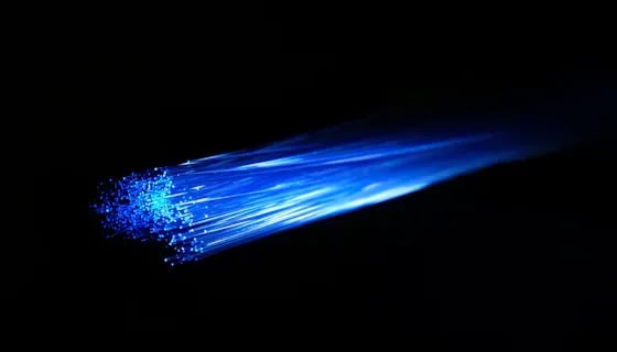 Close-up of illuminated blue fiber optic strands fanning out against a black background.