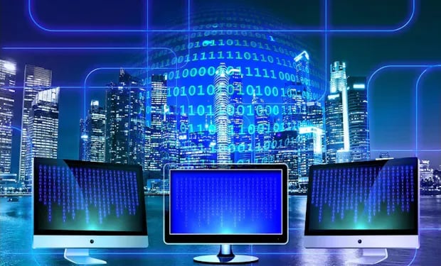 Three computer monitors displaying streams of binary code, set against a city skyline at night with a glowing globe of binary digits overhead.