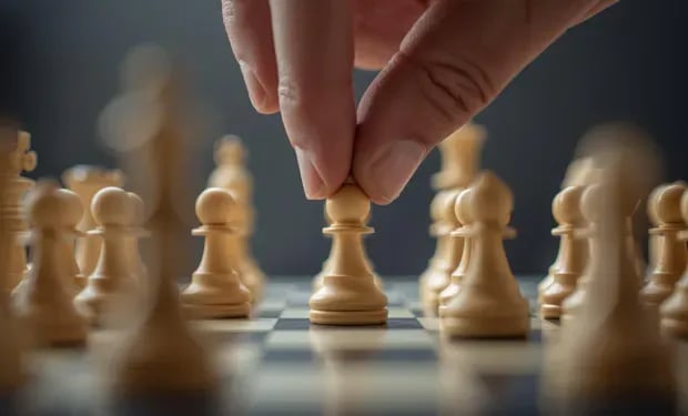 A hand moves a white pawn forward across a chessboard of pawns, evoking the first strategic move in choosing a data quality vendor.